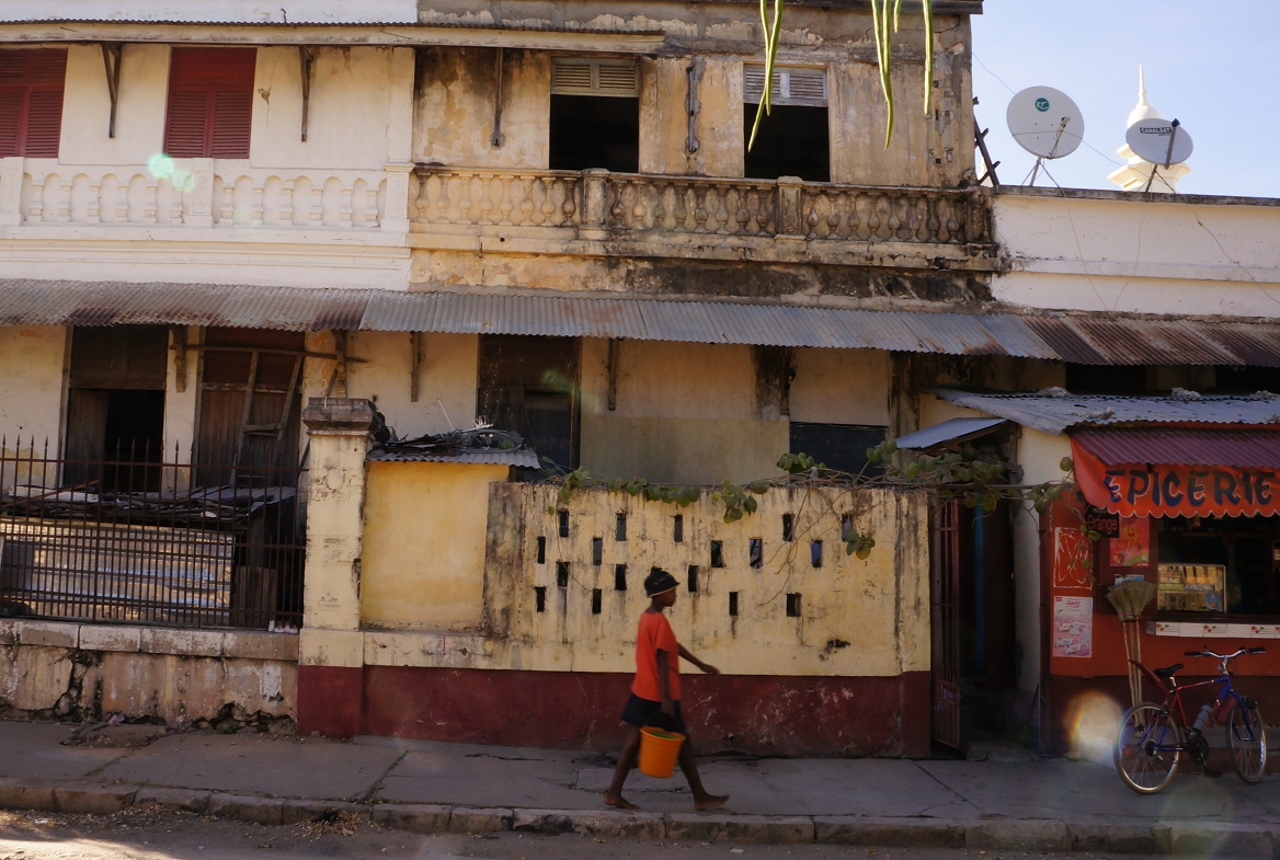 Crumbling building, girl with orange bucket